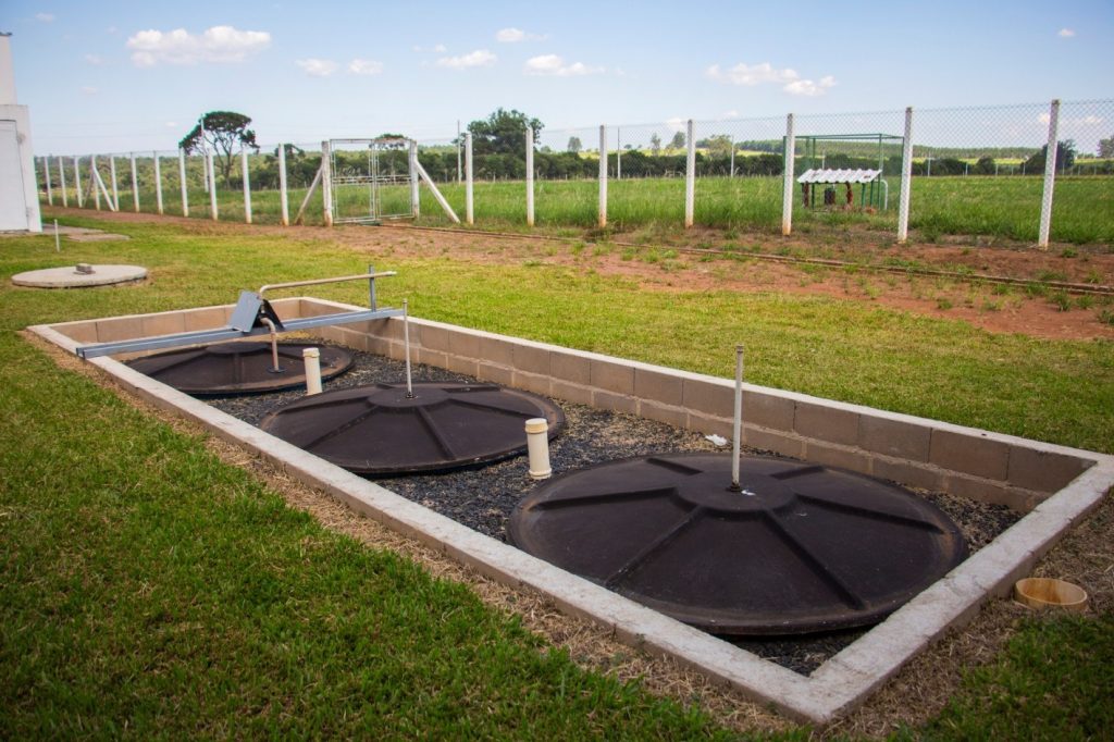 Em campo aberto, instalação de solução alternativa de saneamento básico.