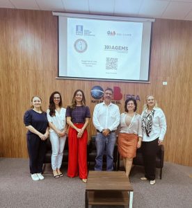 Cinco servidoras da AGEMS posam ao lado de professor na abertura do curso Direito Econômico e Regulação / OAB MS, na sede da entidade.