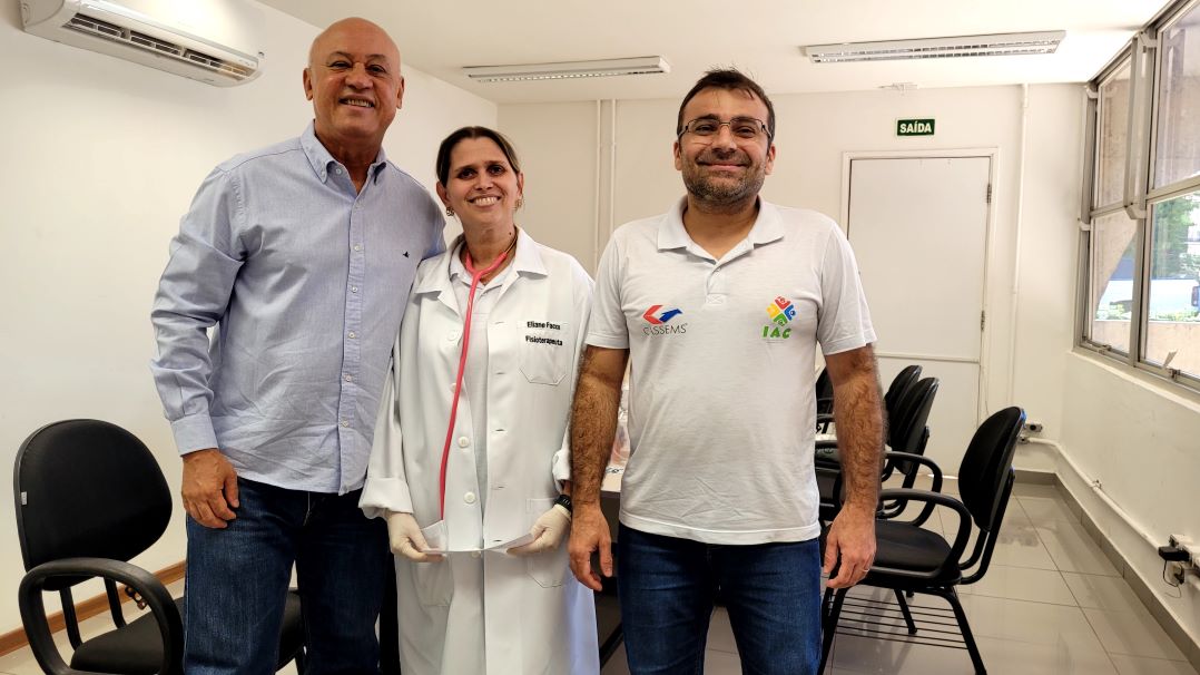 Carlos Alberto de Assis, usando camisa social e jeans, posa, em pé, ao lado de profissionais do programa VIVA SAÚDE, usando jaleco ou camiseta branca do projeto.