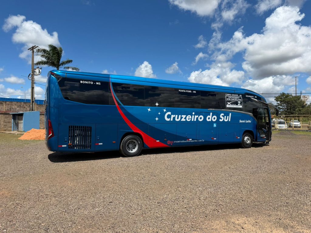 Vista lateral de ônibus da Viação Cruzeiro do Sul estacionado em um pátio. O veículo é azul escuro com inscrições brancas.